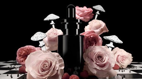 a bottle of luminous day & night silver serum on a chess board surrounded by roses, raspberries and illustrated mushrooms 